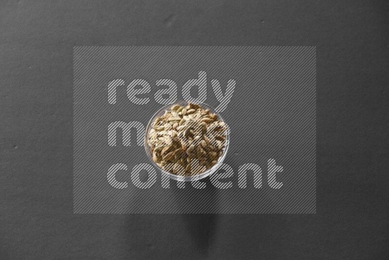 A glass bowl full of cardamom on black flooring