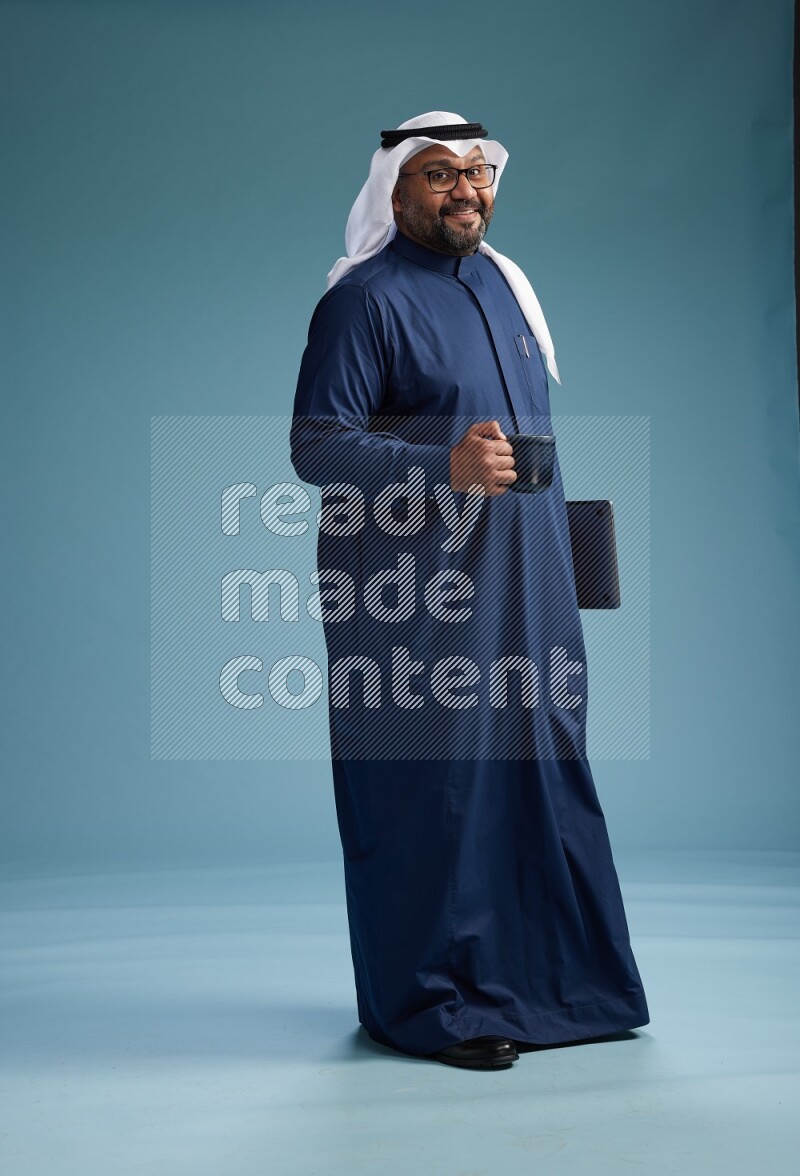 Saudi Man with shimag Standing drinking coffee on blue background