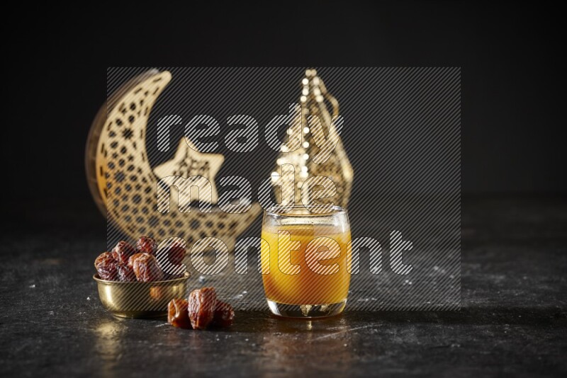 Dates in a metal bowl with qamar el din beside golden lanterns in a dark setup