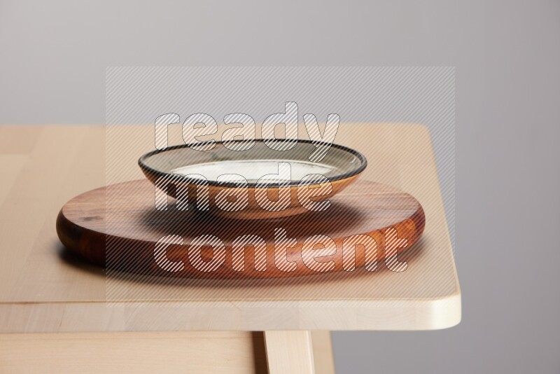 multi-colored pottery Plate placed on a dark colored wooden tray on the edge of wooden table