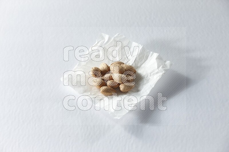 Almonds on a crumpled piece of paper on a white background in different angles