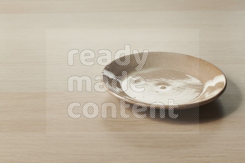 A beige pottery plate on light wooden background