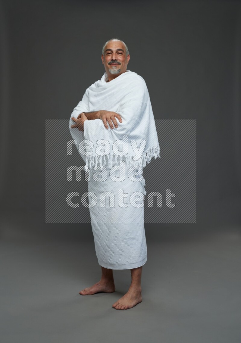 A man wearing Ehram Standing Interacting with the camera on gray background