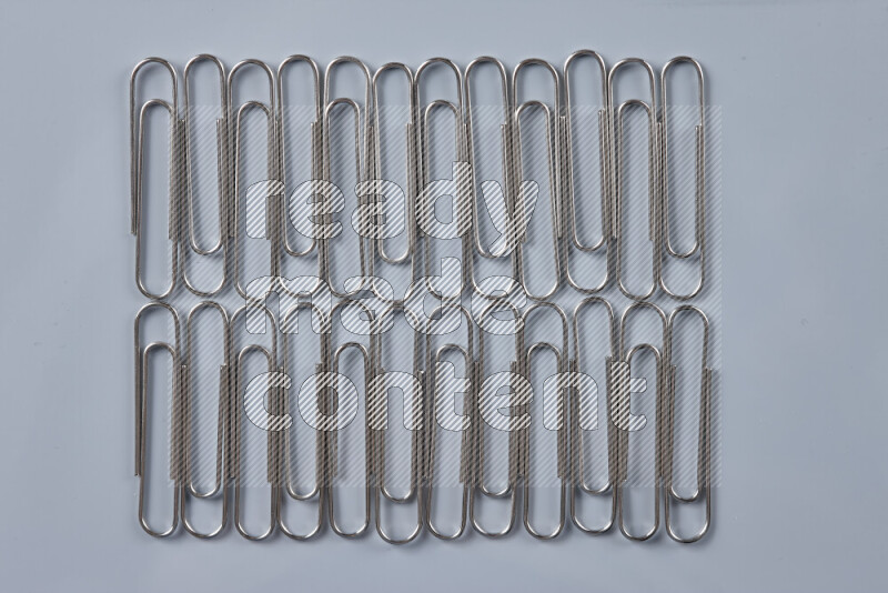 Silver paper clips isolated on a grey background