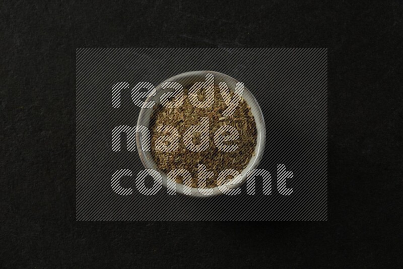 multi color round sauce bowl filled with herbs on grey textured countertop