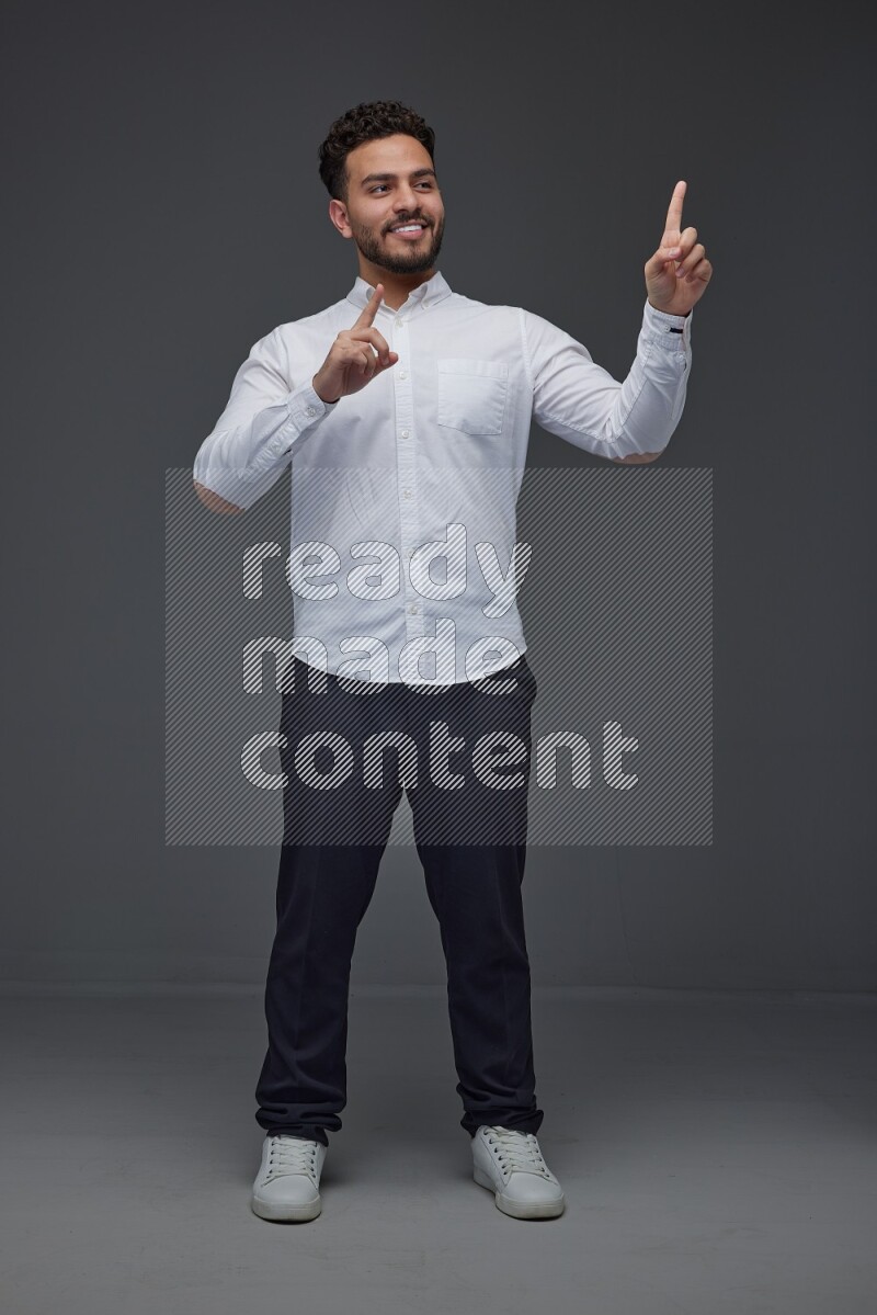 A man wearing smart casual standing and making multi hand gestures eye level on a gray background