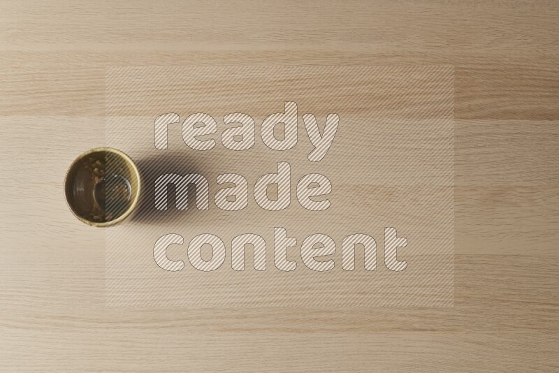 A multicolored pottery cup on light wooden background
