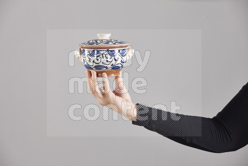 A woman in black abaya holding different pottery essentials in different positions
