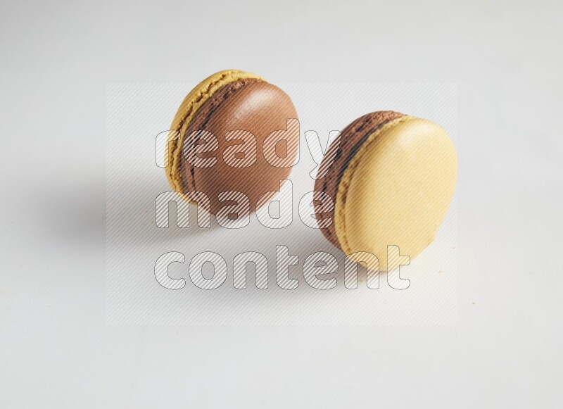 45º Shot of two Yellow and Brown Chai Latte macarons on white background