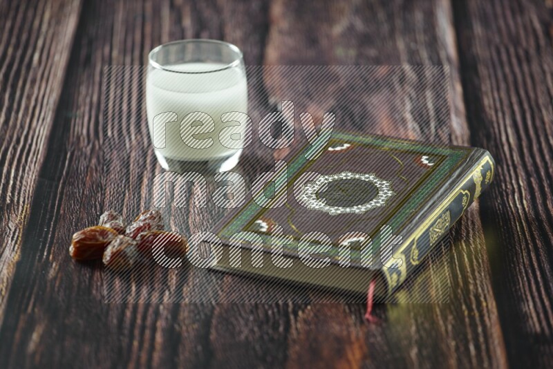 Quran with dates, prayer beads and different drinks all placed on wooden background