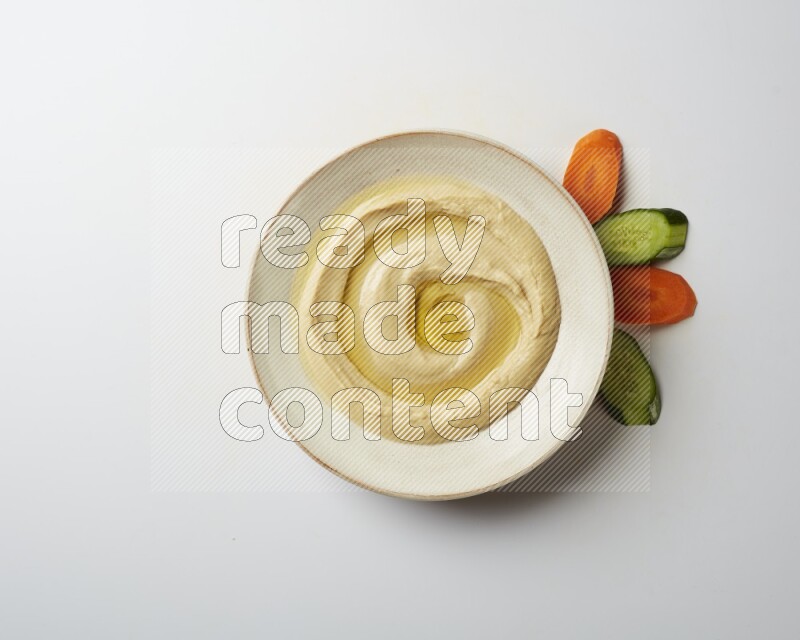 Hummus in a pottry plate garnished with olive oil on a white background