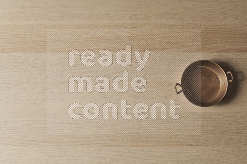 A small copper pan on light wooden background
