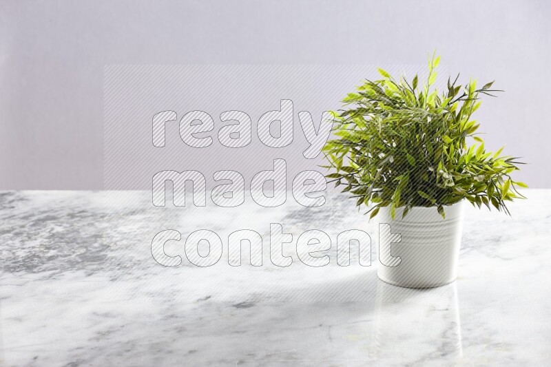 Green artificial plant in white pot on light grey marble background