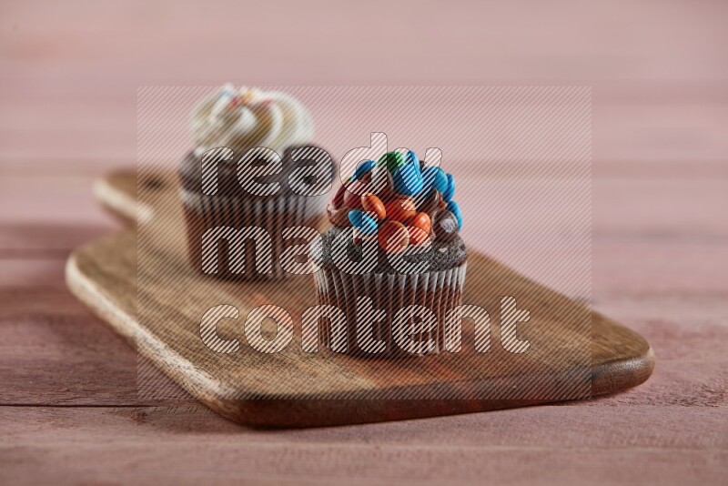 Chocolate mini cupcake topped with m&ms on a wooden board