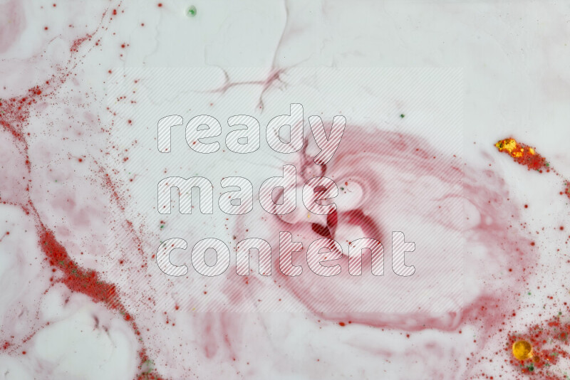 The image captures a splatter of yellow, red and green paint over a white backdrop