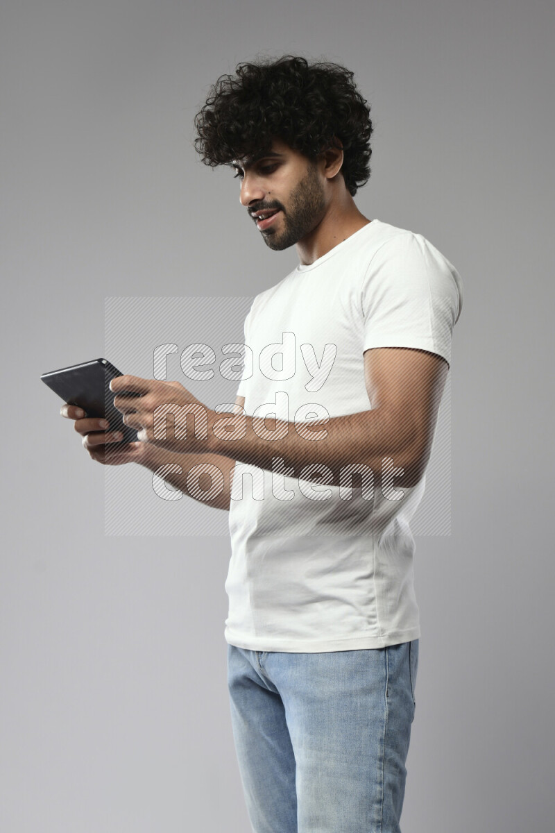 A man wearing casual standing and gaming on a tablet on white background