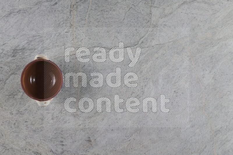 A multicolored pottery pot with its lid on grey marble background