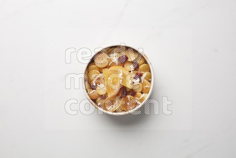 Top-view shot of orange candy cereal pancakes in a round bowl on white background