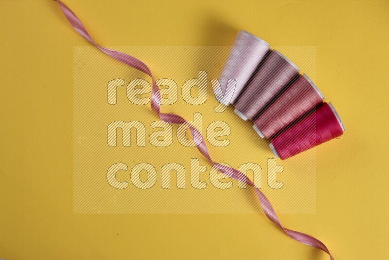 مجموعة من أدوات الخياطة والتفصيل زهرية اللون على خلفية صفراء