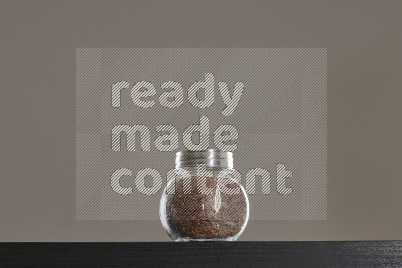 Flax seeds in a glass jar on black background