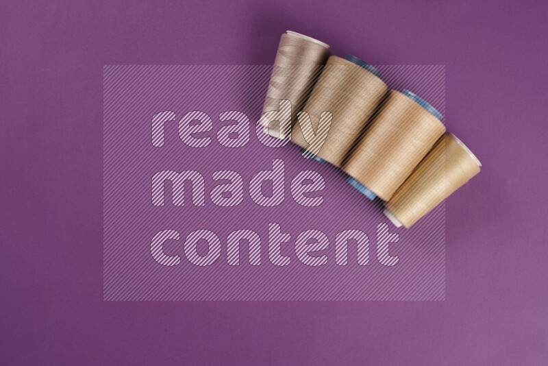 مجموعة من أدوات الخياطة والتفصيل باللون البيج على خلفية أرجوانية