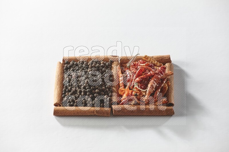 مربعان من أعواد القرفة ممتلئان بالفلفل الحار المجفف وحبوب الفلفل الأسود علي خلفية بيضاء