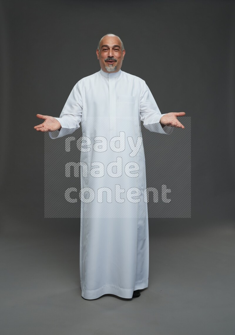 Saudi man without shomag Standing Interacting with the camera on gray background