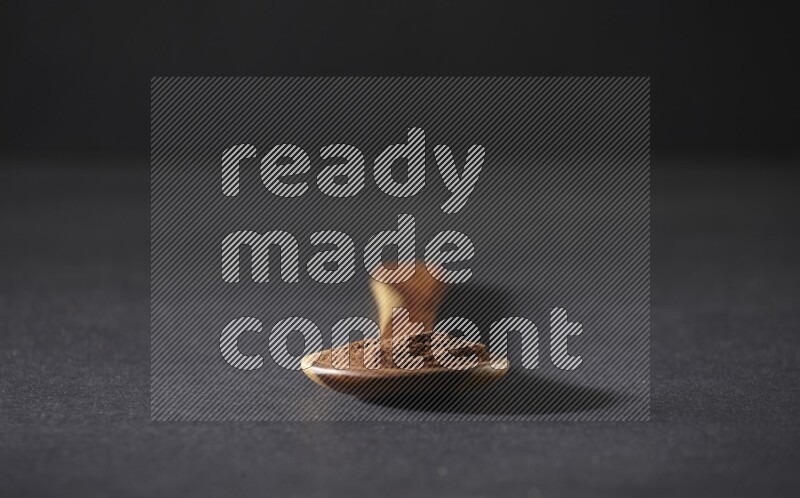 بودرة القرنفل في ملعقة خشبية علي خلفية سوداء