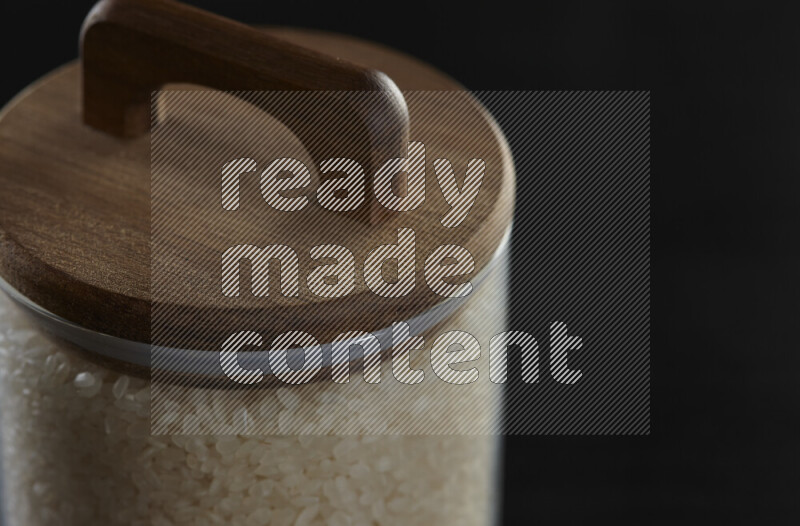 White rice in a glass jar on black background