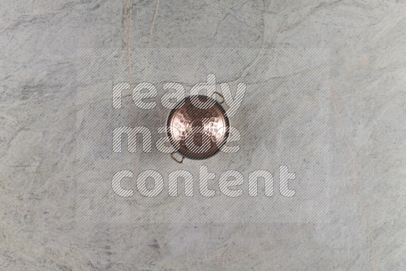 A small copper pot on grey marble background