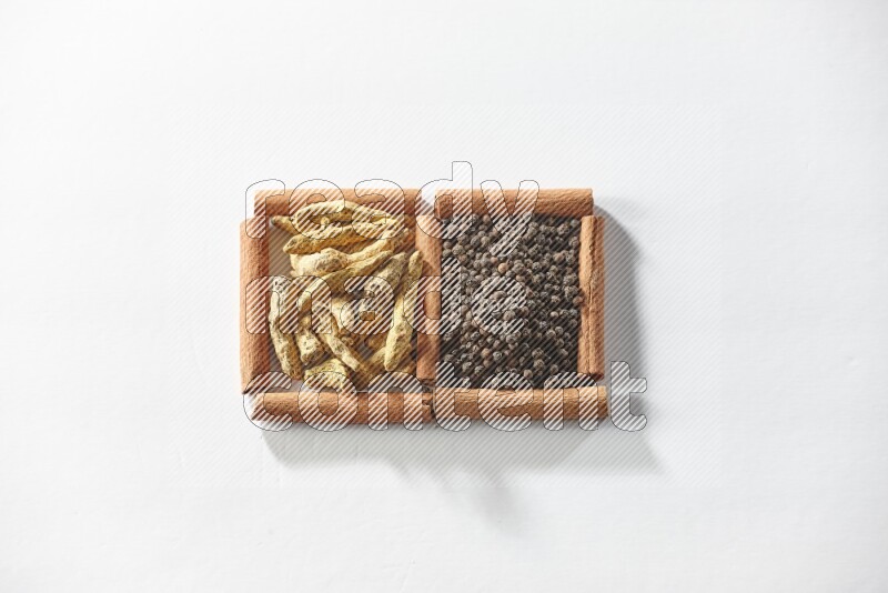 2 squares of cinnamon sticks full of black peppers and turmeric fingers on white flooring
