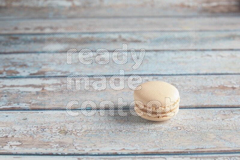 45º Shot of White Caramel fleur de sel macaron on light blue wooden background
