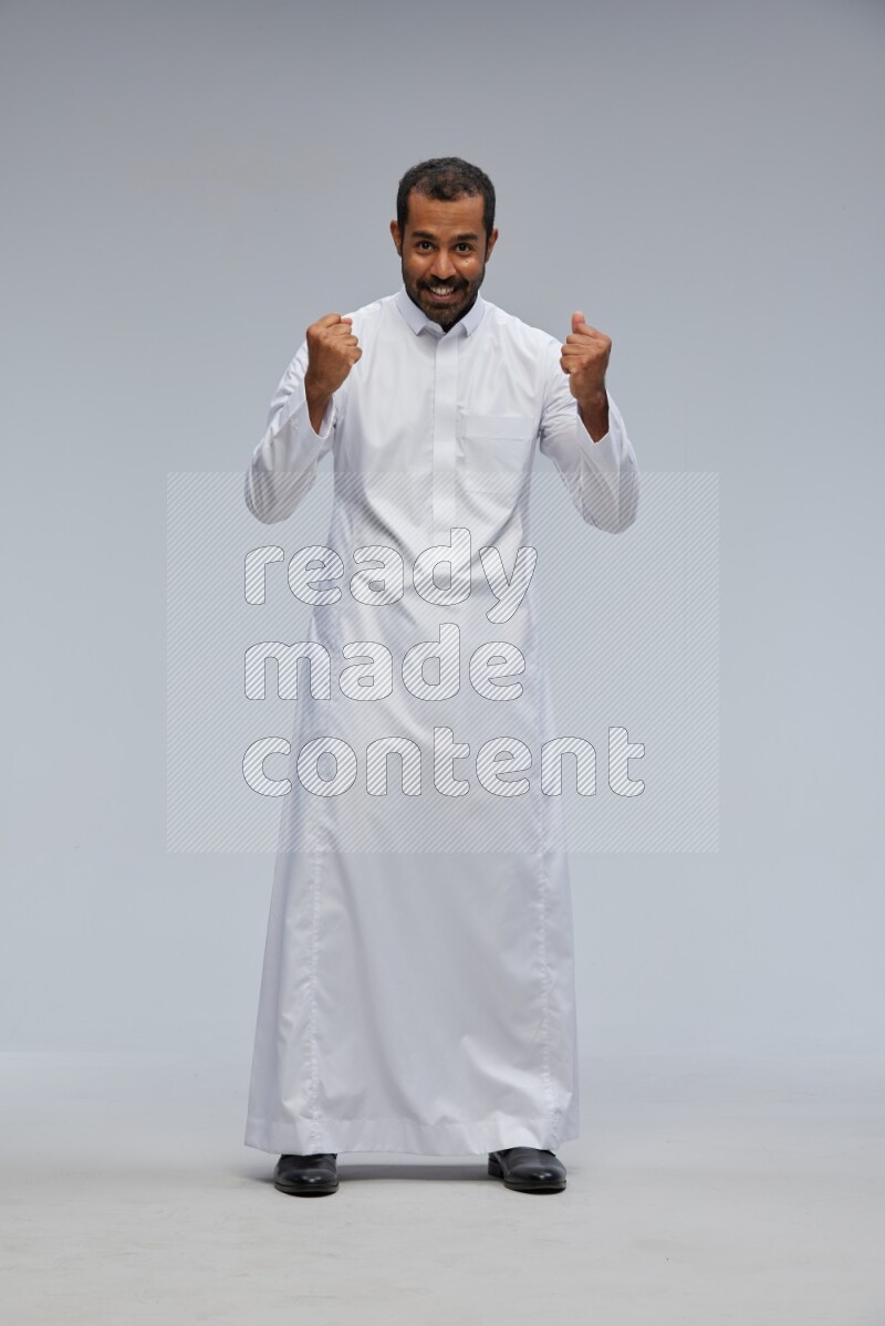 Saudi man Wearing Thob standing interacting with the camera on Gray background