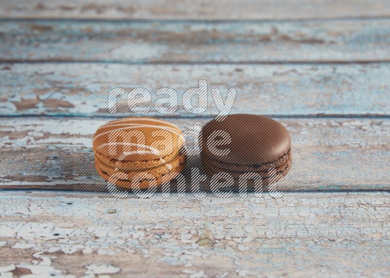 45º Shot of of two assorted Brown Irish Cream, and Brown Dark Chocolate macarons on light blue background