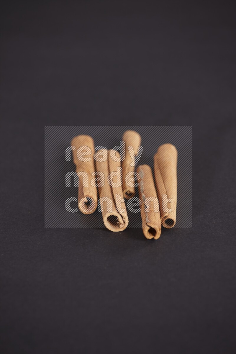 Cinnamon sticks stacked on black flooring