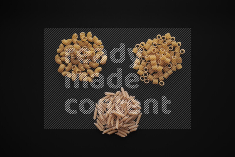 Different pasta types in bunches on black background