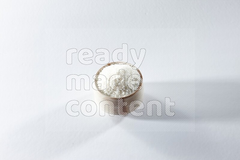 A beige ceramic bowl full of desiccated coconut on a white background in different angles