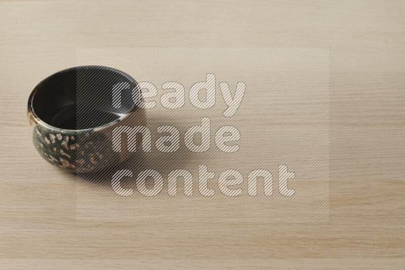 A multicolored pottery bowl on light wooden background