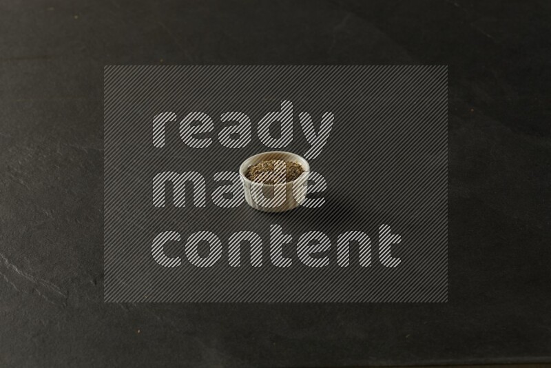 white ceramic round sauce bowl filled with herbs on grey textured countertop