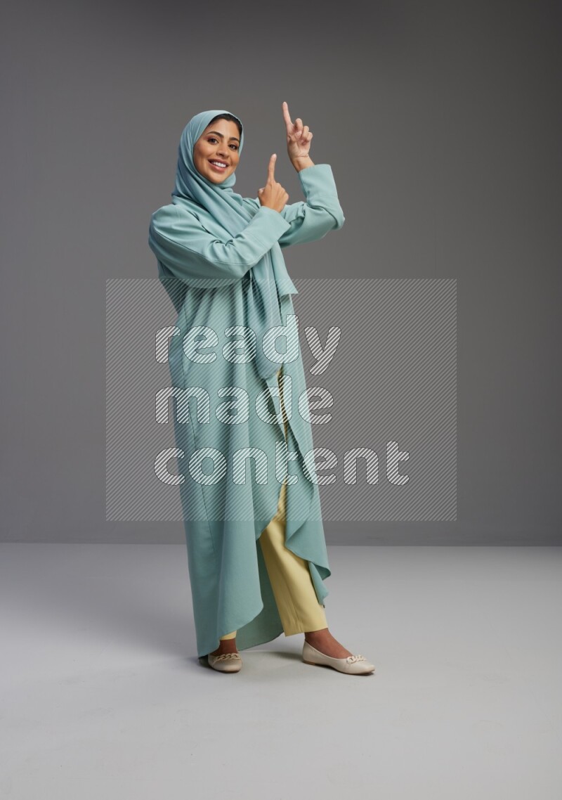 Saudi Woman wearing Abaya standing interacting with the camera on Gray background