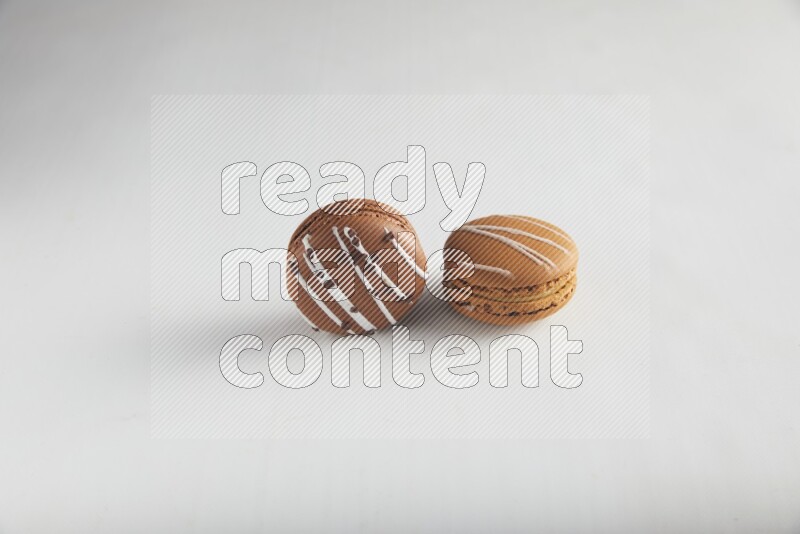 45º Shot of of two assorted Brown Irish Cream, and Brown white Chocolate Caramel macarons on white background