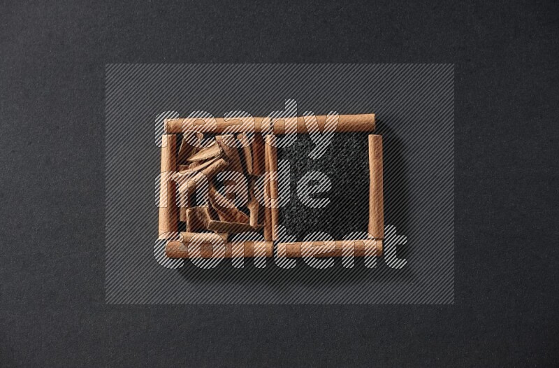 2 squares of cinnamon sticks full of black seeds and cinnamon on black flooring