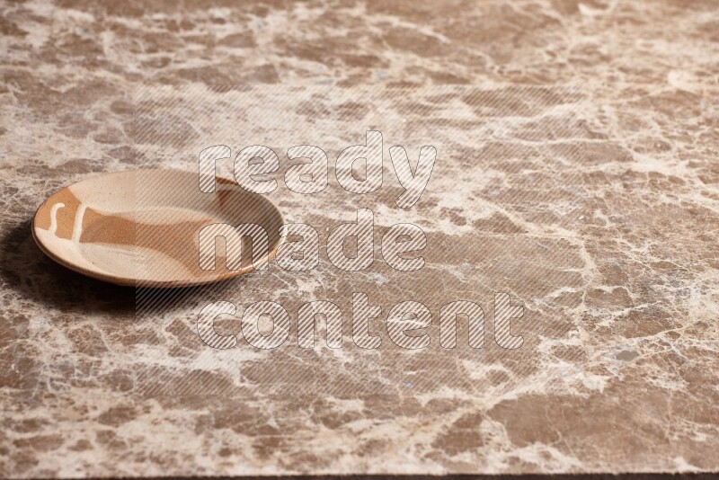A multicolored pottery plate on beige marble background