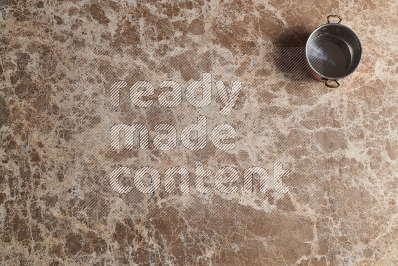 A small copper pot on beige marble background
