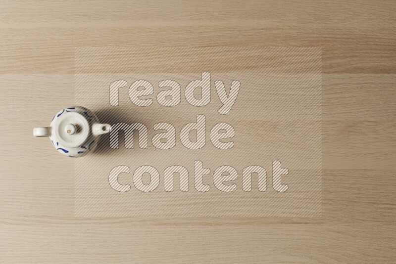 A pottery teapot on light wooden background