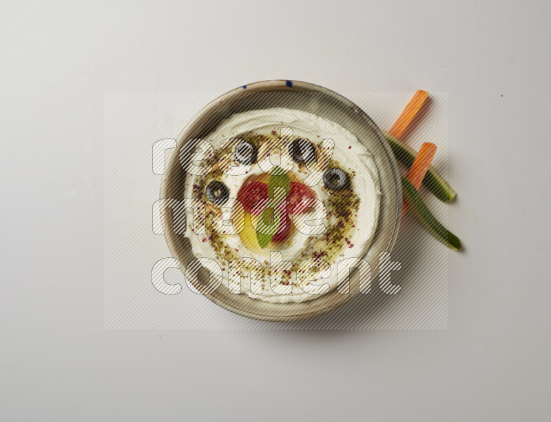 Lebnah garnished with cherry tomato, mint, olives & pine nuts in a grey pottery plate on a white background