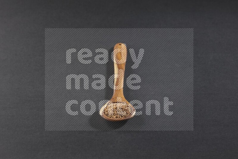 ملعقة خشبية كبيرة ممتلئة ببذور الخردل علي خلفية سوداء