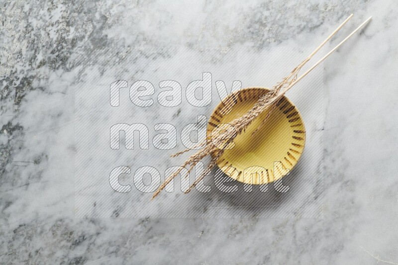 Wheat stalks on multicolored pottery plate on grey marble background