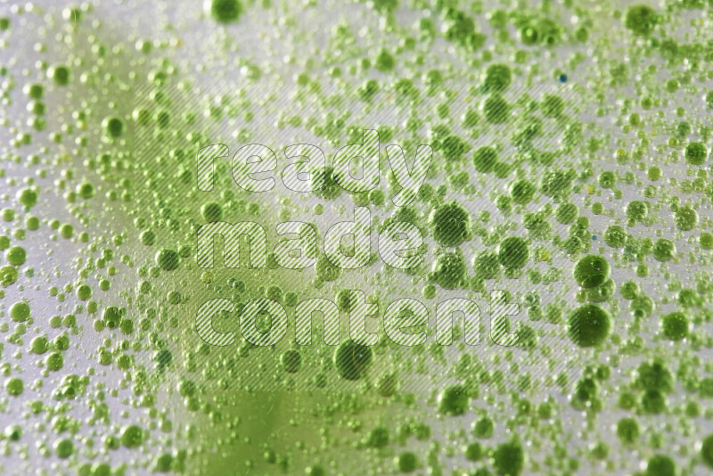 Close-ups of abstract green watercolor drops on oil Surface on white background