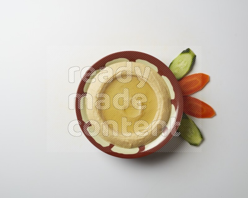 Hummus in a traditional plate garnished with olive oil on a white background